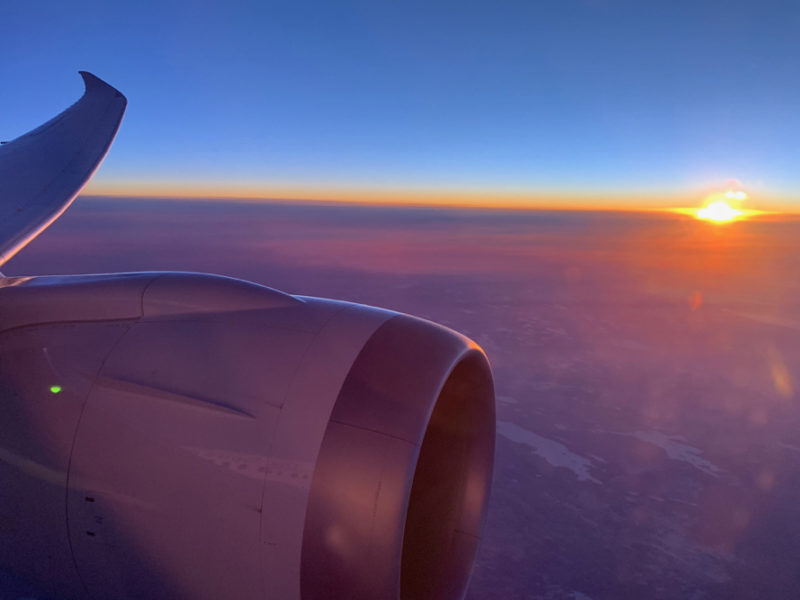 an airplane wing with the sun in the background