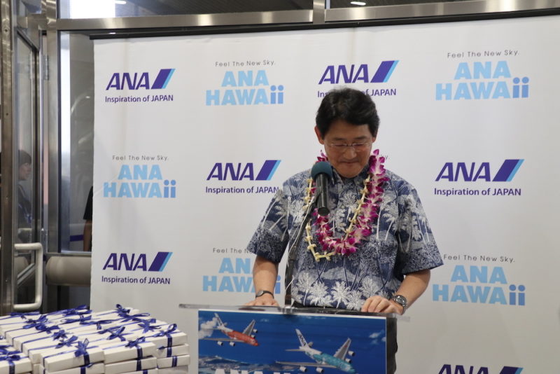 a man standing at a podium with a lei around his neck