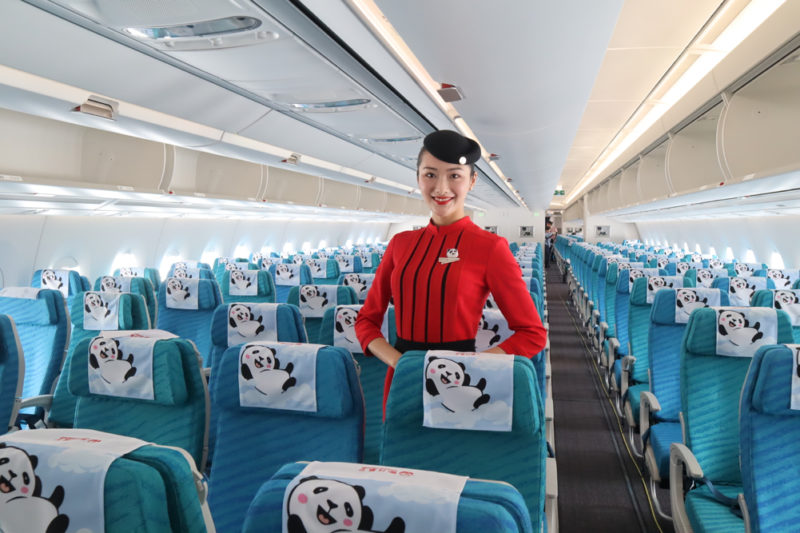 a woman in a red uniform standing in a row of blue chairs with pandas on them