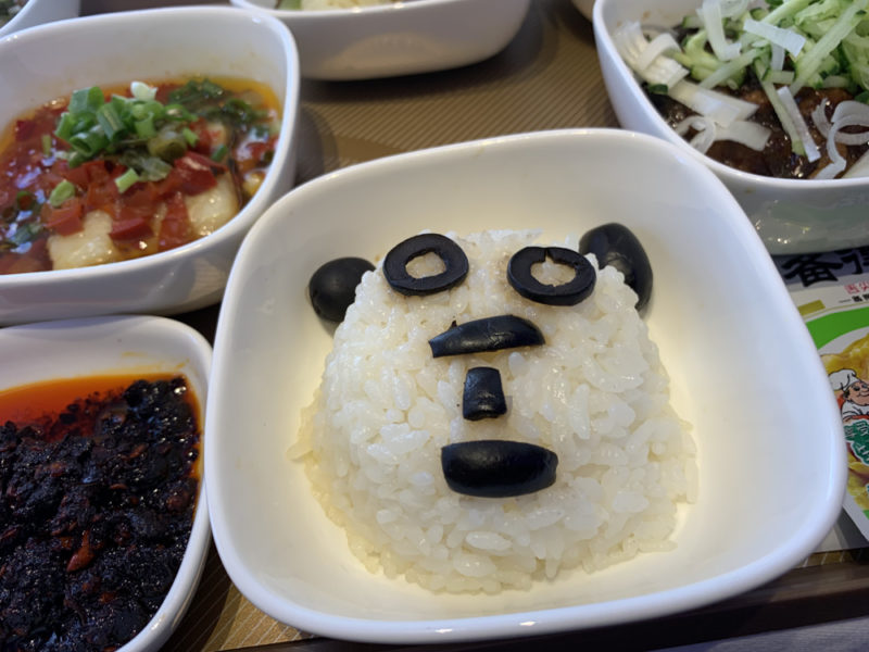 a bowl of rice with black olives in the shape of a bear
