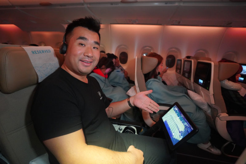 a man sitting in an airplane with a tablet and headphones