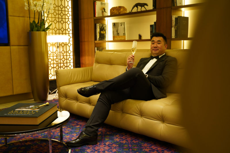a man sitting on a couch holding a glass of champagne