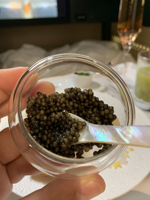 a hand holding a jar of black caviar