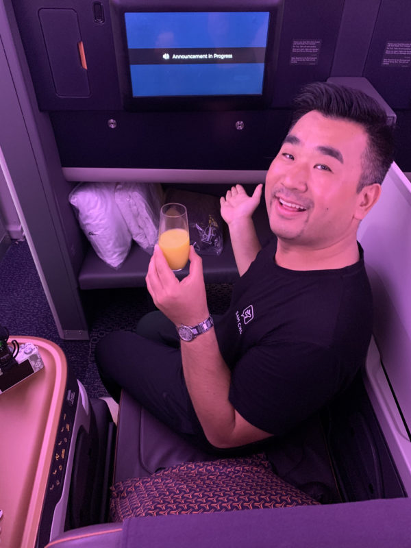 a man sitting on a seat holding a glass of orange juice