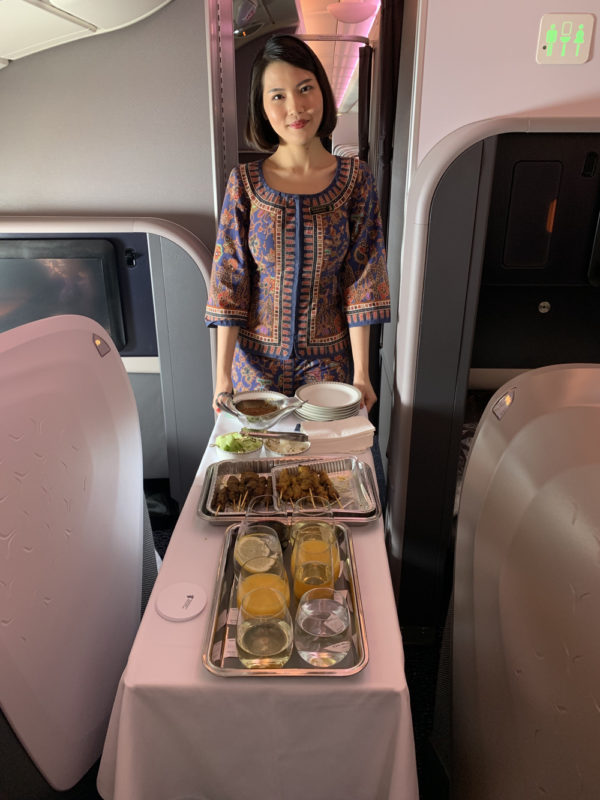 a woman standing in an airplane with food on a table