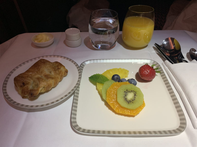 a plate of fruit and croissant on a table