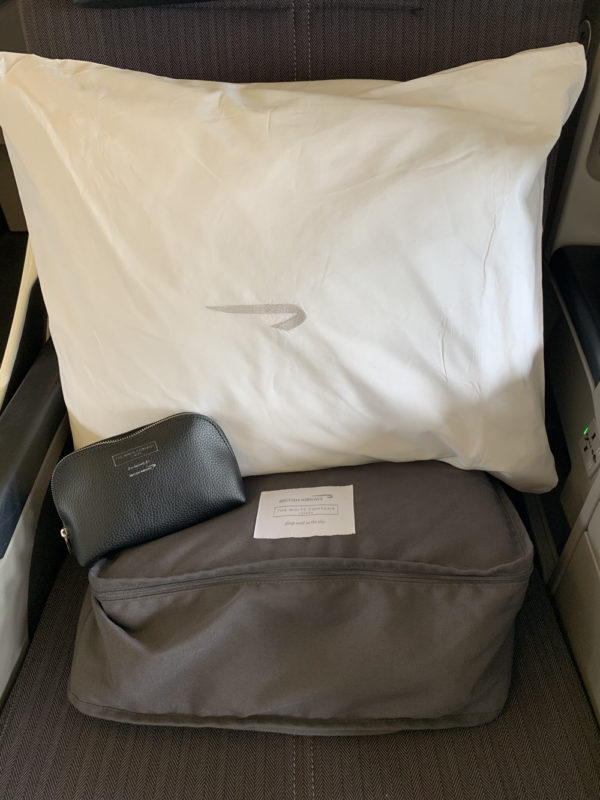 a white pillow and a black purse on a seat