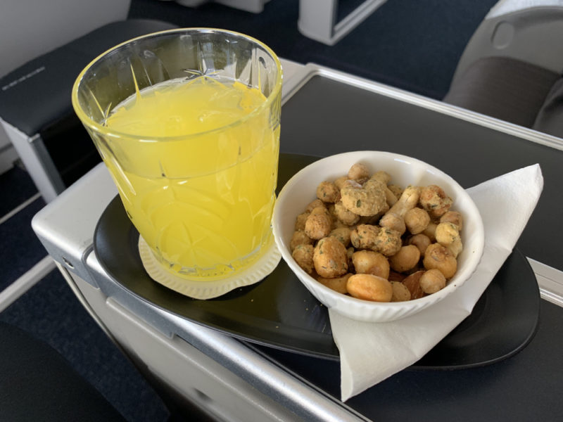a bowl of peanuts and a drink on a tray