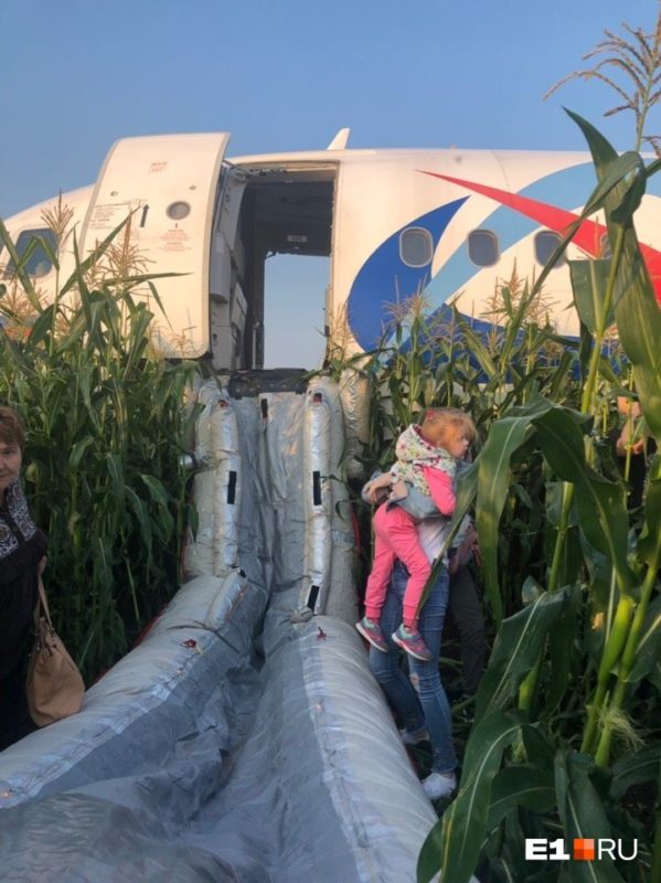 a woman carrying a child in front of an airplane