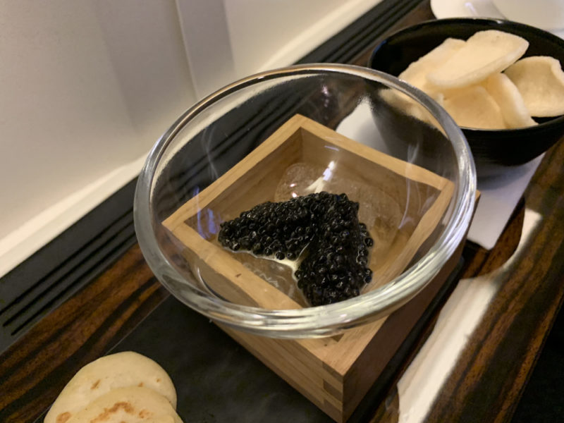 a bowl of black caviar in a wooden box