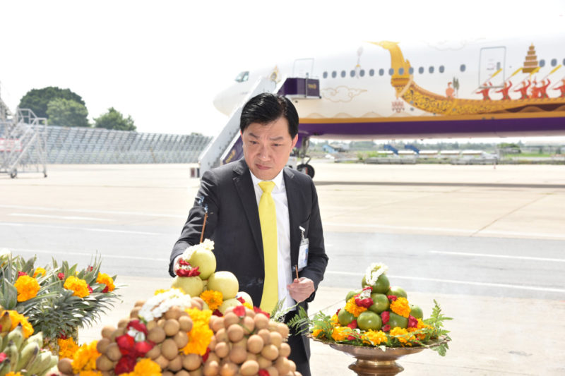 a man in a suit and tie standing next to a table with fruit and flowers