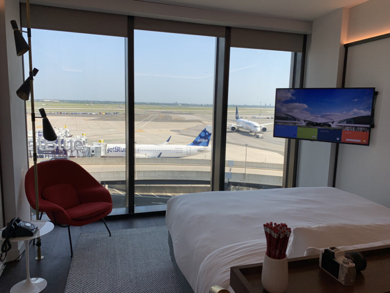 a room with a bed and a television and a window with airplanes