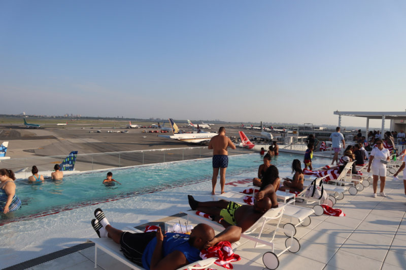 people sitting on lounge chairs near a pool