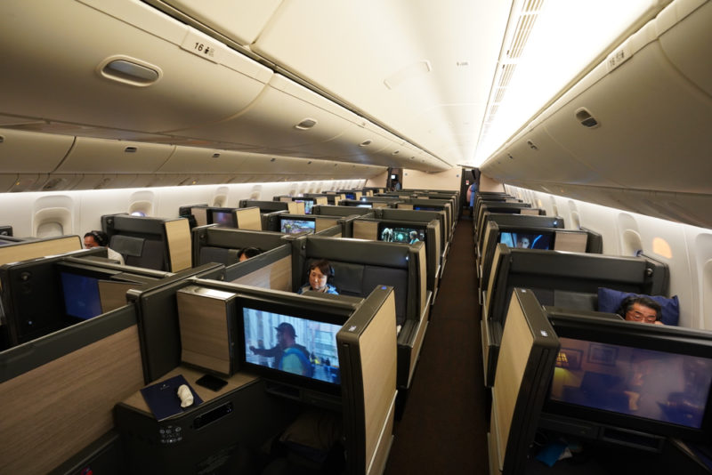 a group of people sitting in a row of seats with monitors