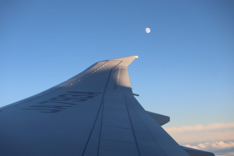 the wing of an airplane with the moon in the background