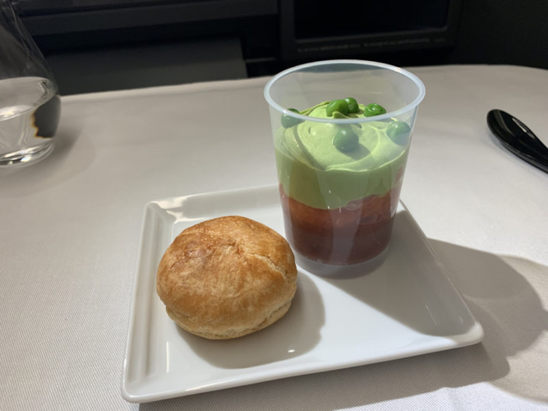 a plate with a pastry and a cup of food on it