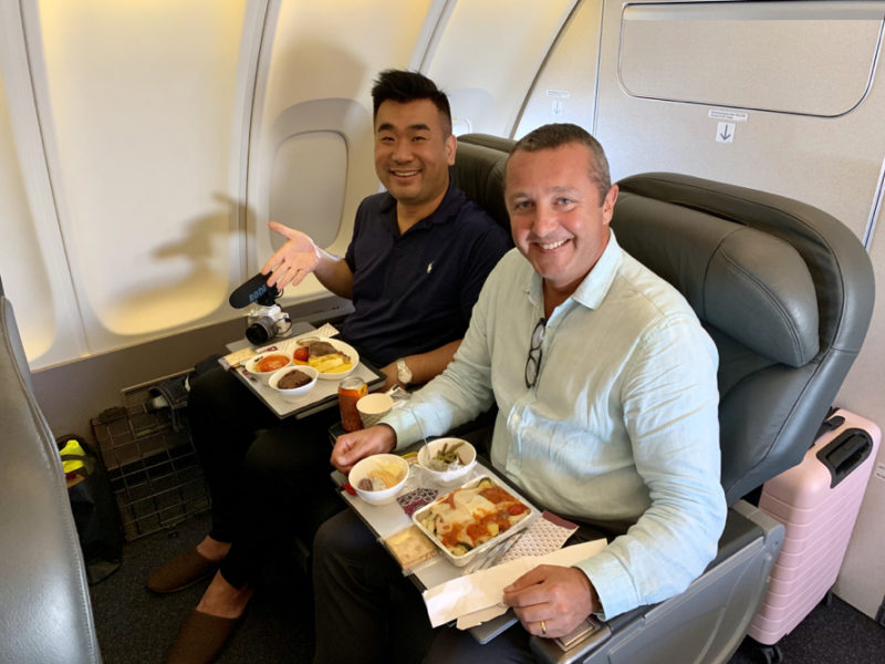 two men sitting in a chair eating food