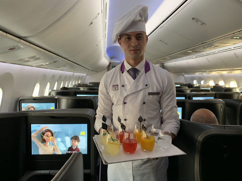 a man in a uniform holding a tray of drinks