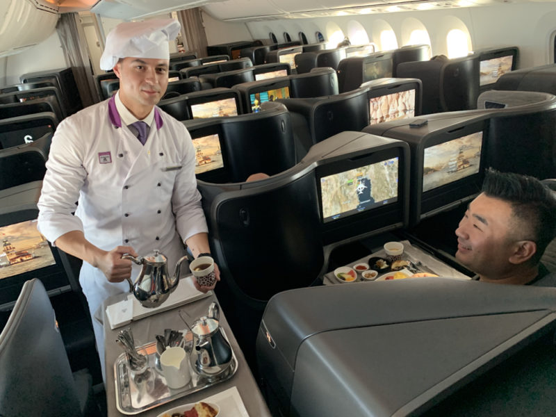 a man in a chef's uniform serving food in an airplane
