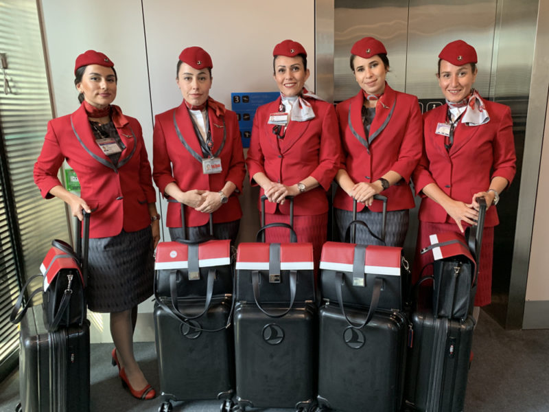 a group of women wearing red uniforms and holding luggage