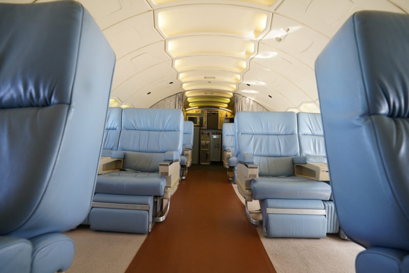 the inside of an airplane with blue chairs
