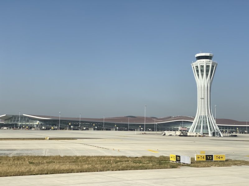 a white tower in front of a large airport