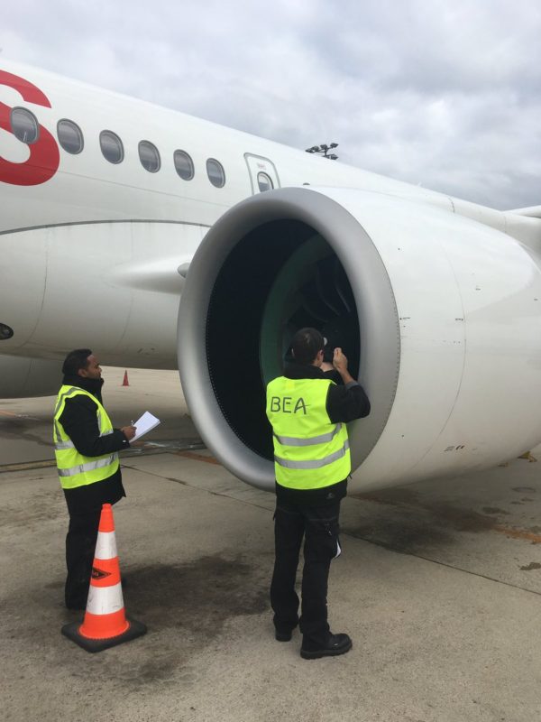 men standing next to a large jet engine