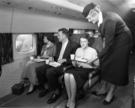 a flight attendant serving food to passengers