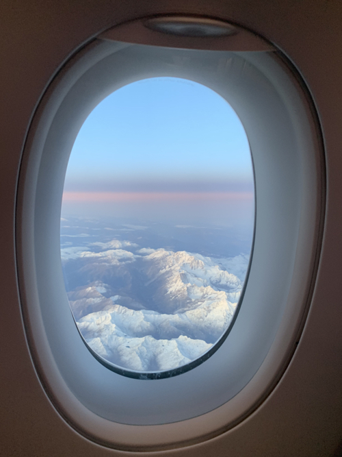 a window of an airplane with snow covered mountains