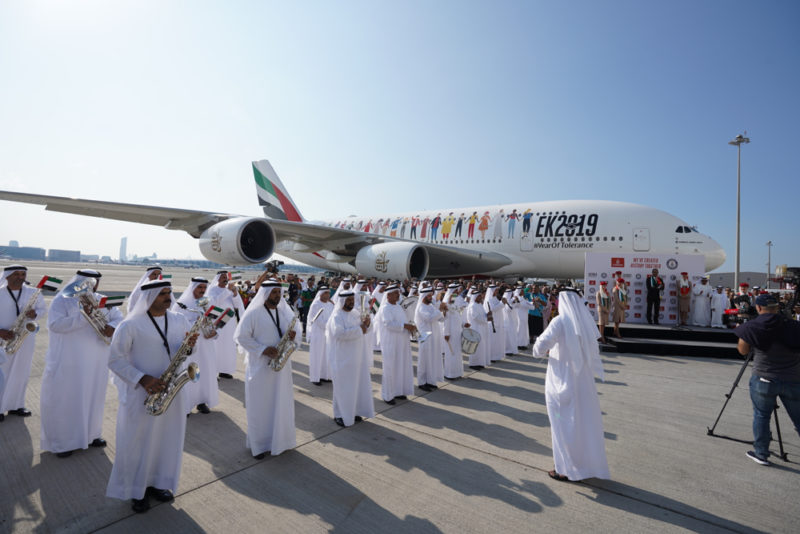 a group of people in white robes standing in front of an airplane