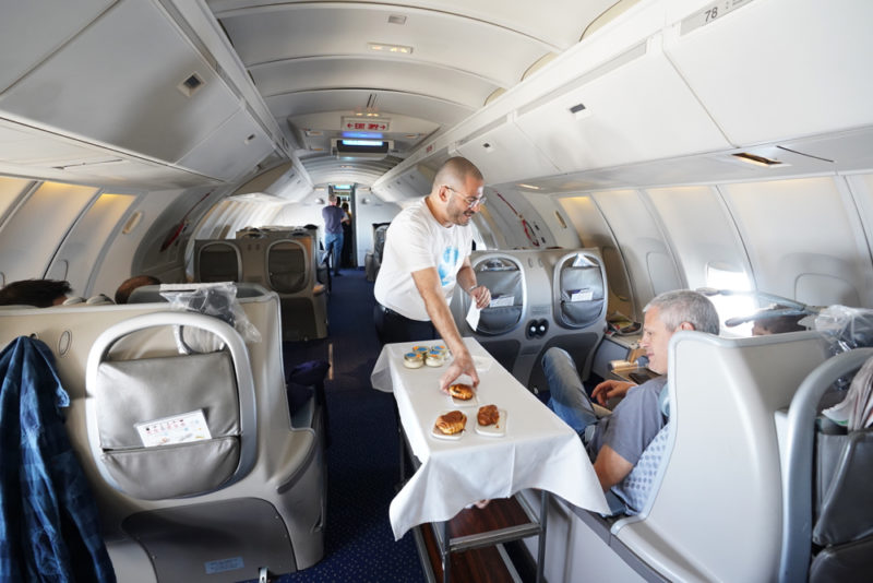 a man serving food to a man on an airplane