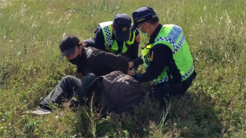 a group of police officers helping a man with a backpack