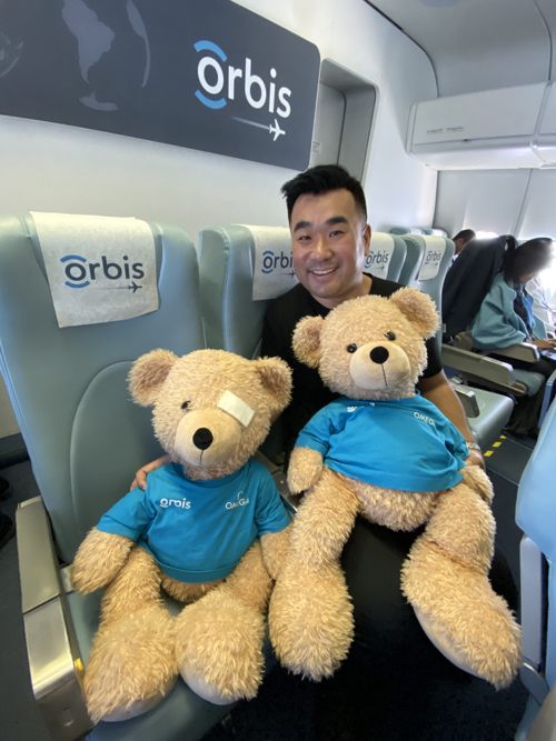 a man sitting on a plane with two stuffed bears