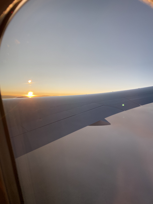 the wing of an airplane with the sun setting in the background