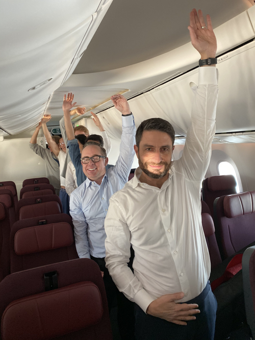a group of people in an airplane with their arms raised