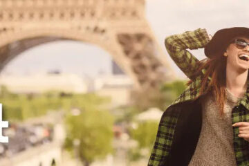 a woman in a sweater and a scarf in front of a tower