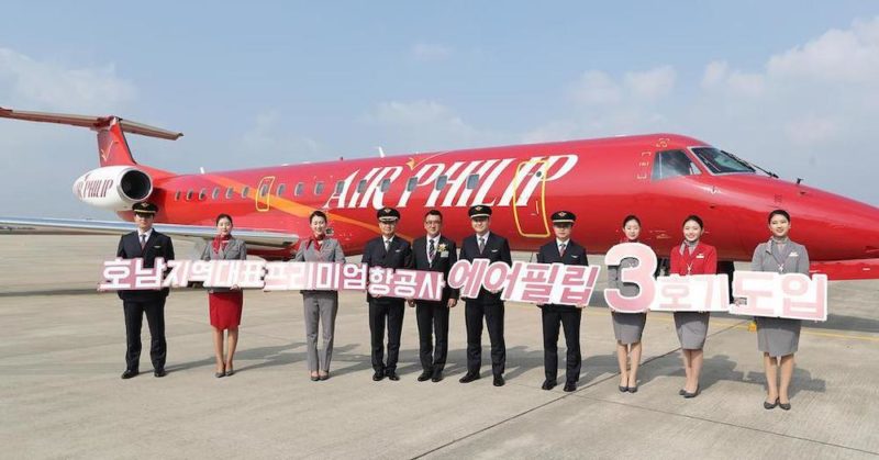 a group of people holding signs in front of a plane