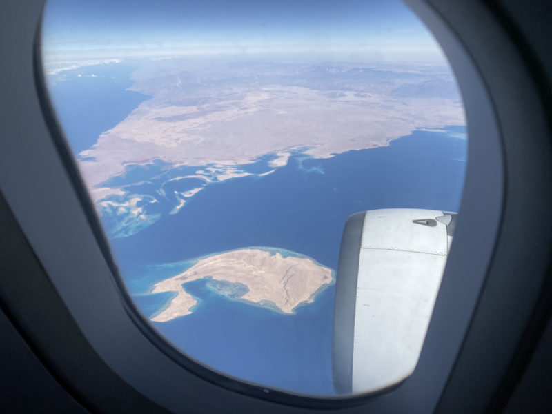 Airplane window with island visible in the distance