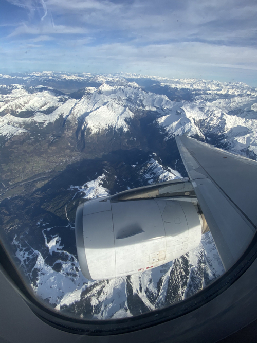 an airplane wing and snow covered mountains