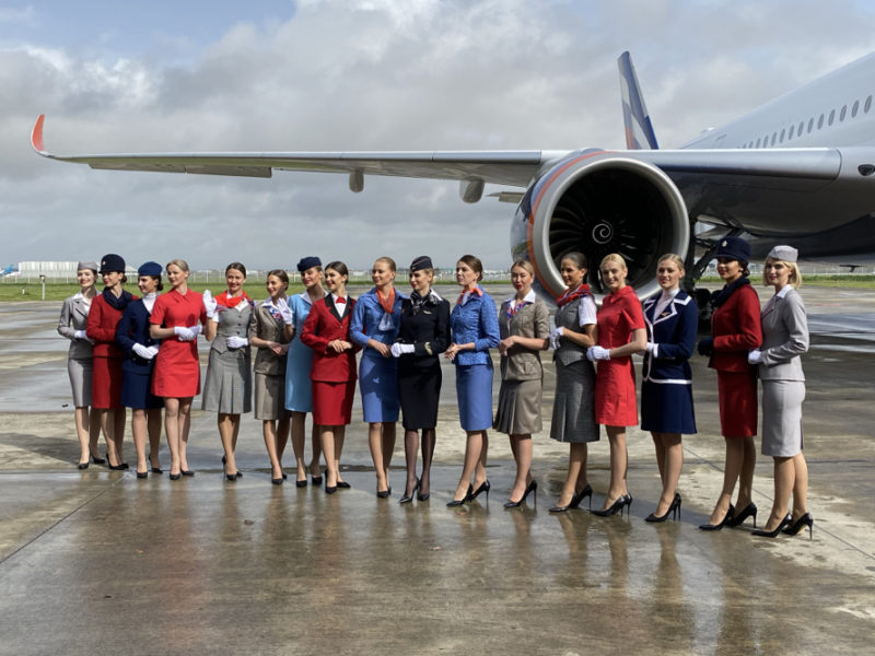 a group of women in uniform standing in front of an airplane