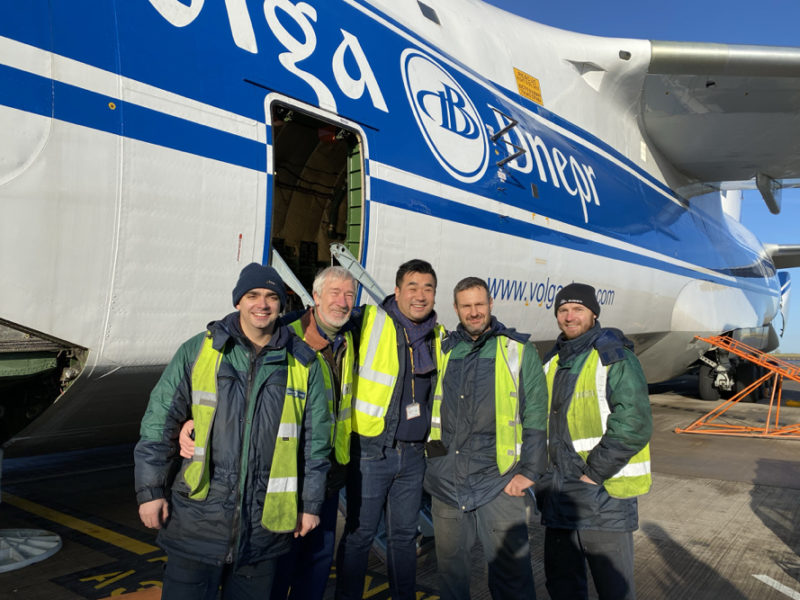 a group of men standing in front of a plane