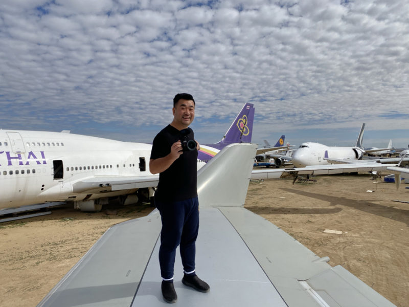a man standing on a wing of an airplane with a camera