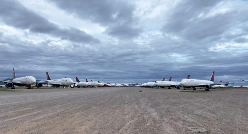 a group of airplanes parked on a dirt field
