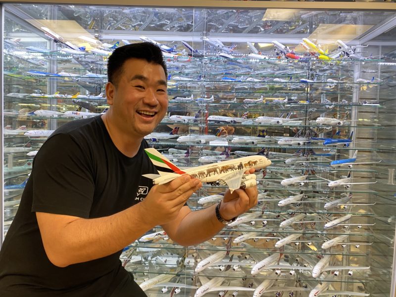 a man holding a model airplane in front of a display of model airplanes