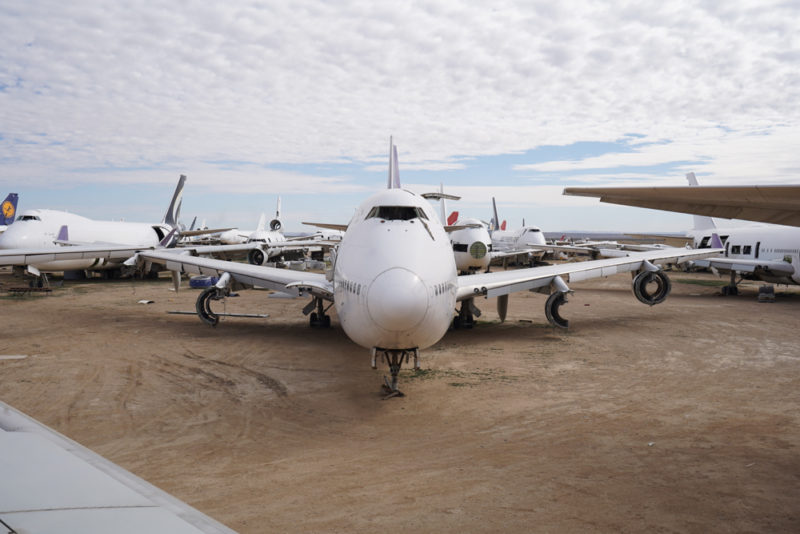 a group of airplanes on a dirt field