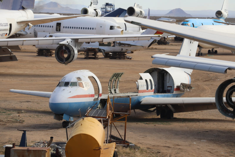 a group of airplanes on a dirt field