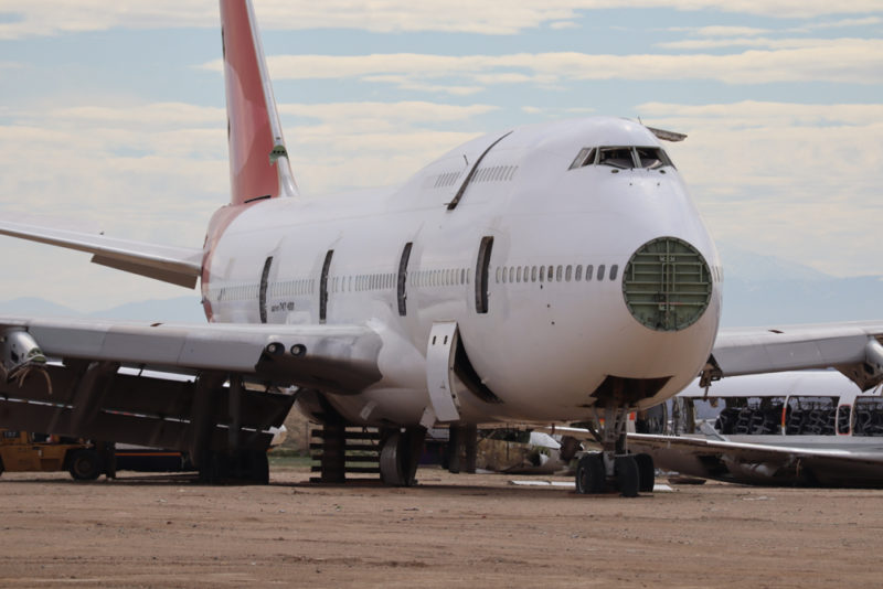 a large white airplane on a dirt field
