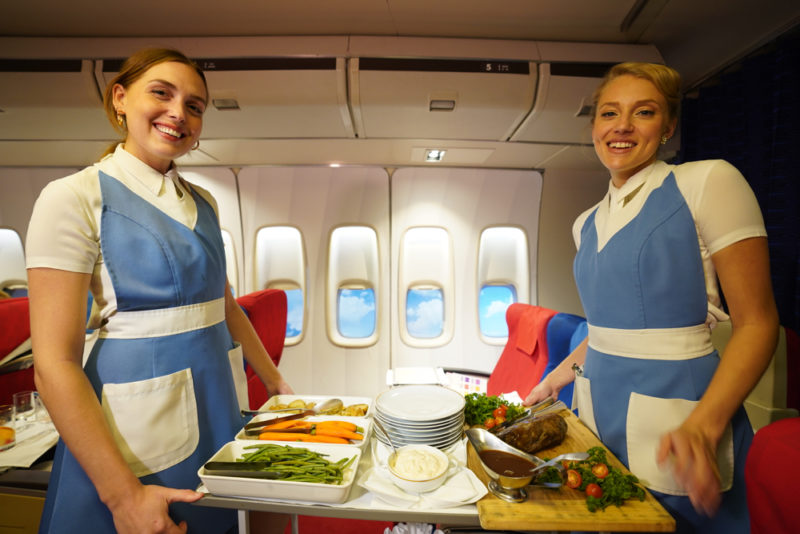 two women in blue uniforms standing in an airplane