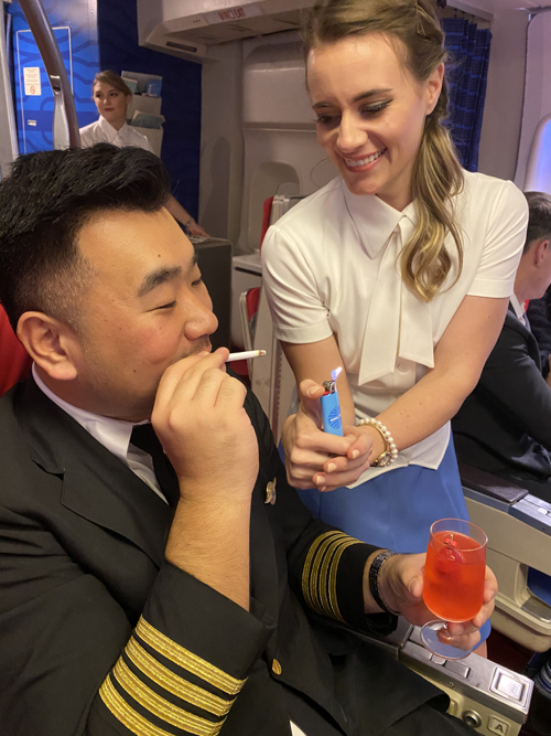 a man smoking a cigarette and a woman sitting on an airplane