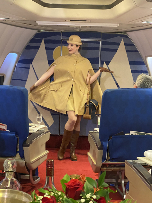 a woman in a cape and hat in an airplane